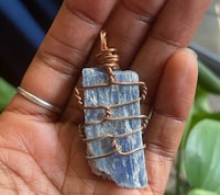 a person holding a blue apatite stone in a copper wire