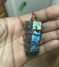 a person holding a labradorite pendant