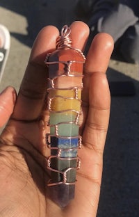 a person holding a multi colored chakra necklace