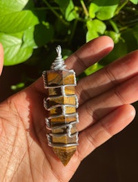 a person holding a tiger eye stone pendant
